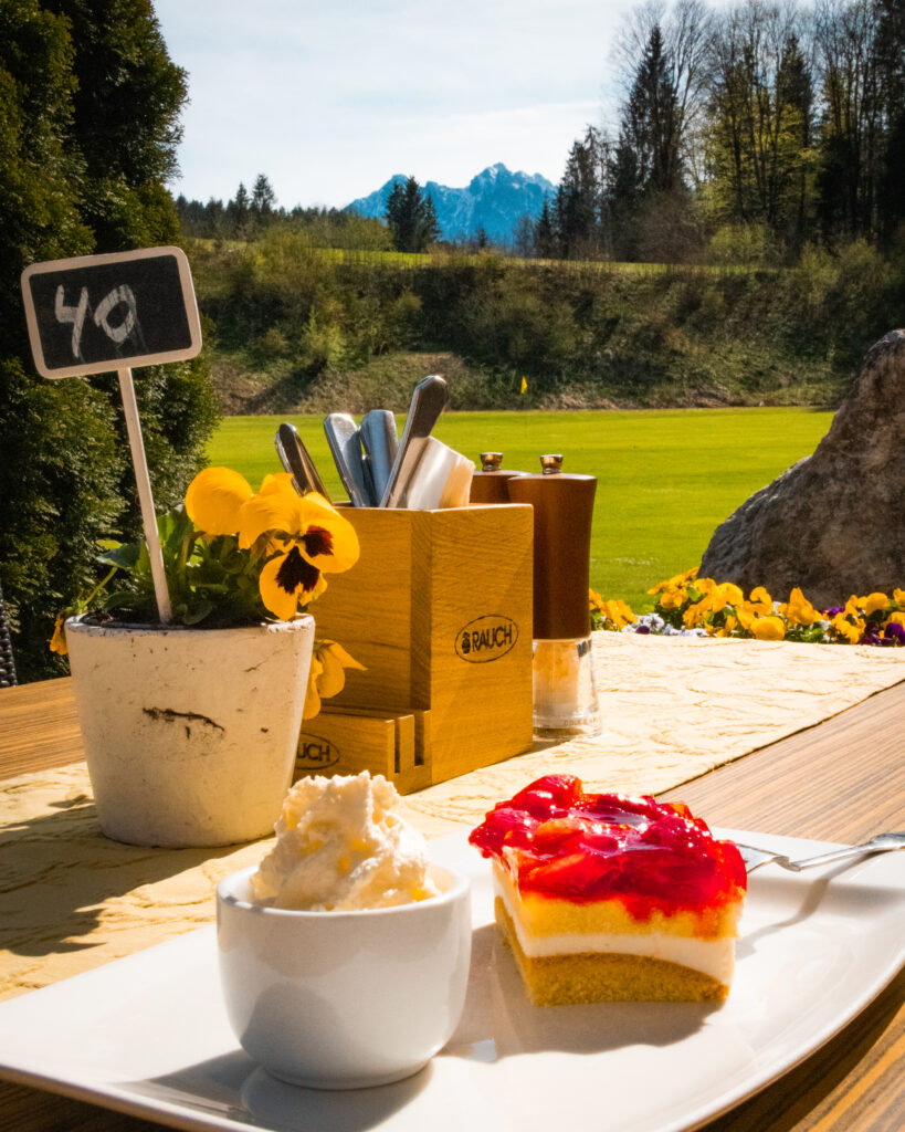 Kaffee und Kuchen mit Sahne auf der Sonnenterrasse des Clubrestaurant des Kaiserwinkl Golf Kössen - Lärchenhof.